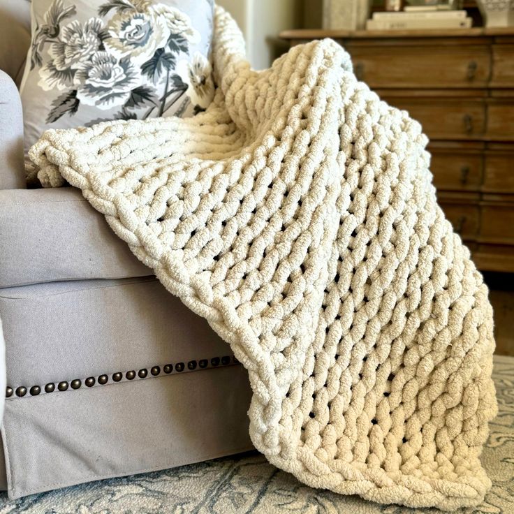 a knitted blanket sitting on top of a couch next to pillows and a chair