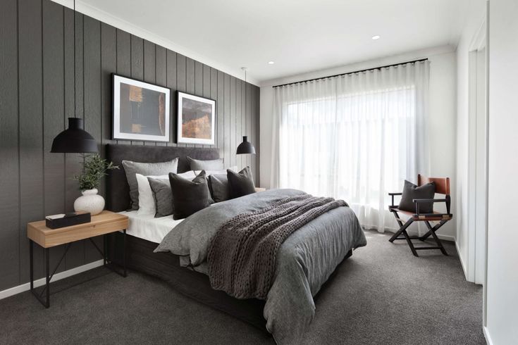 a bedroom with gray walls and white curtains, grey bed linens, black lamps and pictures on the wall