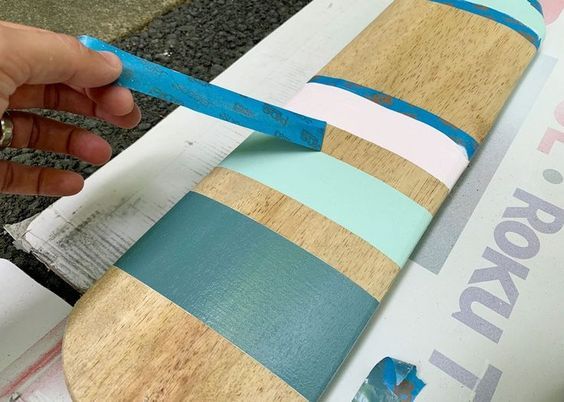 a person holding a pair of scissors next to a surfboard that has been painted blue and pink