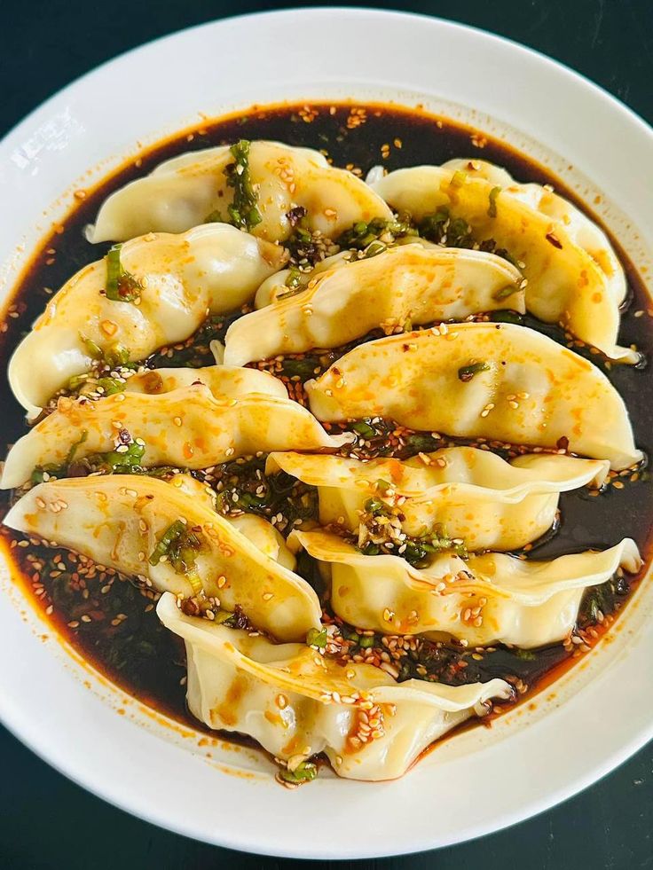 a white plate topped with dumplings covered in sauce