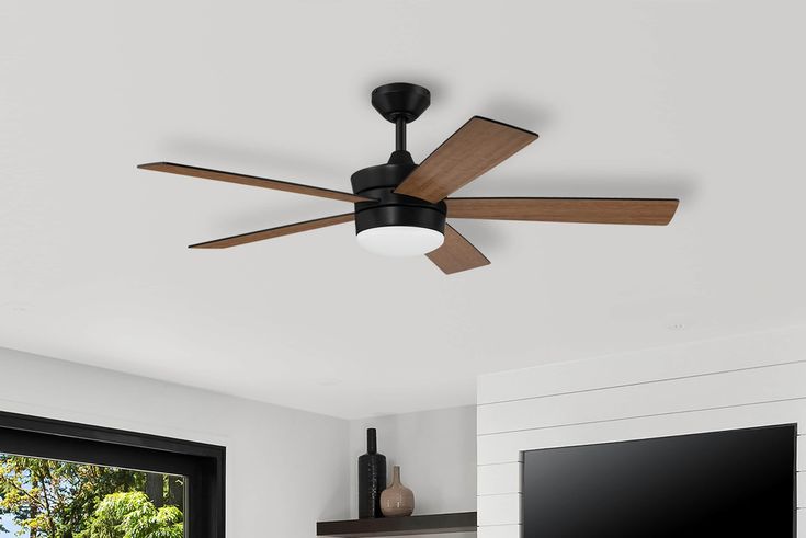 a ceiling fan in a living room with a flat screen tv mounted on the wall