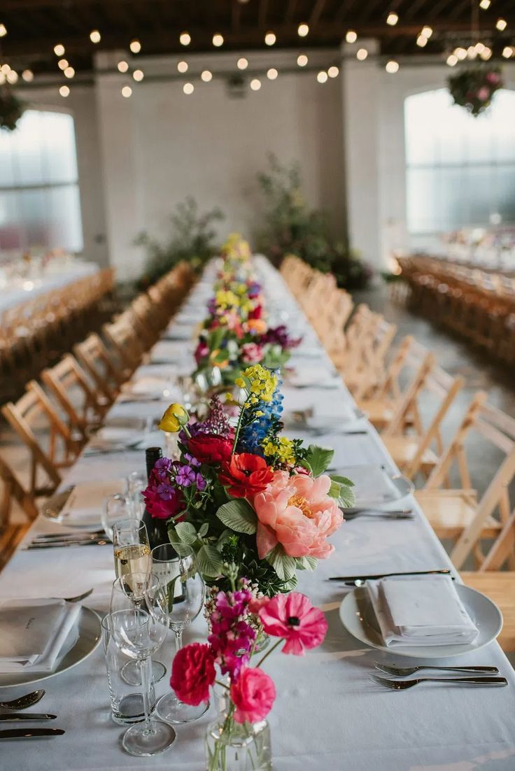 a long table is set up with flowers and wine glasses for an elegant wedding reception