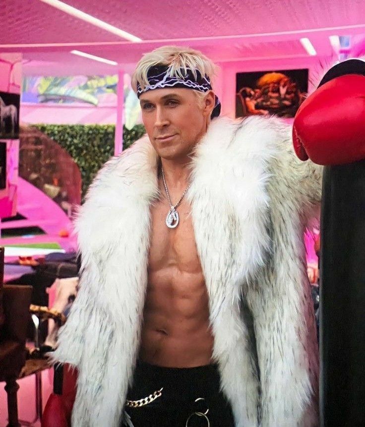 a shirtless man in a white fur coat standing next to a punching bag and boxing gloves