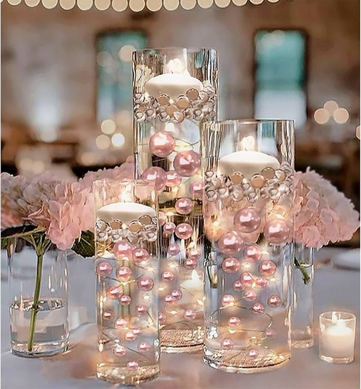 the centerpieces are filled with pink flowers and lit candles in glass vases