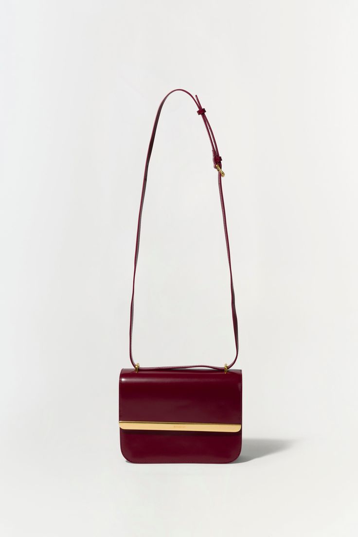 FALL 2024 WOMEN'S COLLECTION The Remy Bag in Oxblood. Featuring a sleek design and gold accent, add sophistication to your outfit with this elegant flap bag. Perfect for day-to-night transitions, it effortlessly combines style and functionality. SIMKHAI Women's Remy Bag in Oxblood Chic Rectangular Flap Bag For Everyday Luxury, Elegant Red Flap Bag, Elegant Gold Flap Bag With Detachable Handle, Chic Flap Bag With Gold-tone Hardware For Formal Events, Chic Flap Bag With Gold-tone Hardware For Formal Occasions, Chic Formal Flap Bag With Gold-tone Hardware, Classic Gold Flap Bag For Office, Burgundy Evening Crossbody Flap Bag, Formal Flap Bag With Fold Over Clasp