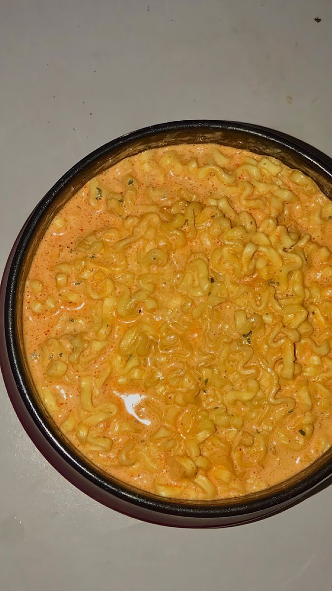 a bowl filled with macaroni and cheese sitting on top of a white table