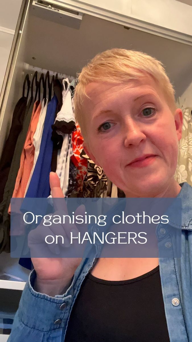 a woman making the peace sign in front of a closet with clothes on hangers