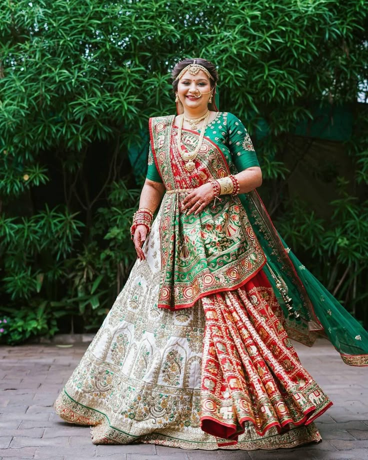 a woman in a green and red lehenga is posing for the camera with her hands on her hips