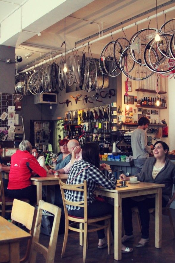 people sitting at tables in a restaurant with bicycles hanging from the ceiling