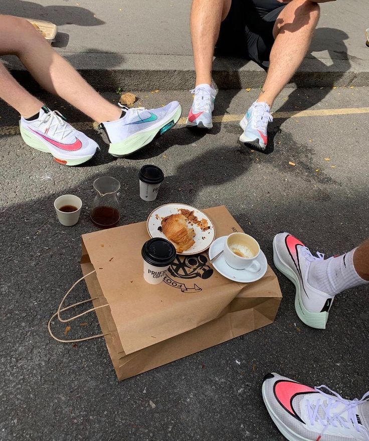 two people sitting on the ground with their feet up next to coffee cups and doughnuts