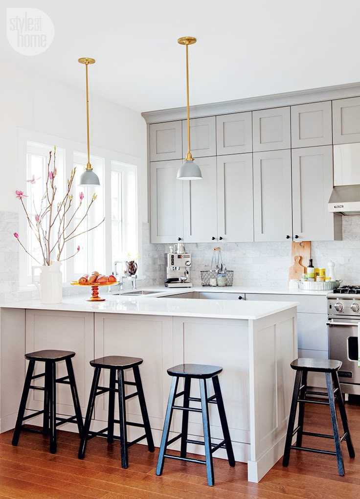 a kitchen with three stools in front of an island and two lights above it