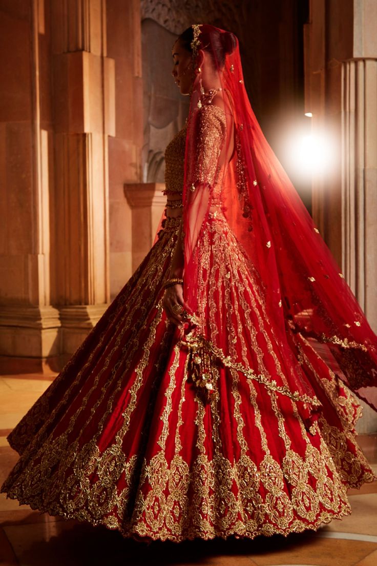 Deep red raw silk lehenga with attached can-can, intricately embroidered in traditional zardozi. Comes with gold embroidered padded choli and tulle dupatta.
Component: 3
Pattern: Embroidered
Type Of Work: Zardozi
Neckline: Sweetheart
Sleeve Type: Half
Fabric: Raw Silk, Tulle
Color: Red
Other Details: 
Tassel hem blouse
Cutwork hem dupatta
Back cut-out with tassel tie-up
Note:
Belt worn by the model is not for sale
The veil worn by the model is not for sale
Occasion: Bride, Wedding - Aza Fashions Red Anarkali Gown For Traditional Ceremonies, Traditional Red Semi-stitched Gown, Red Kundan Lehenga With Dupatta, Red Kundan Sets With Dupatta, Red Dola Silk Lehenga With Sheer Dupatta, Red Anarkali Lehenga With Sheer Dupatta, Traditional Red Gown With Dupatta, Red Semi-stitched Kundan Gown, Red Dola Silk Choli With Sheer Dupatta