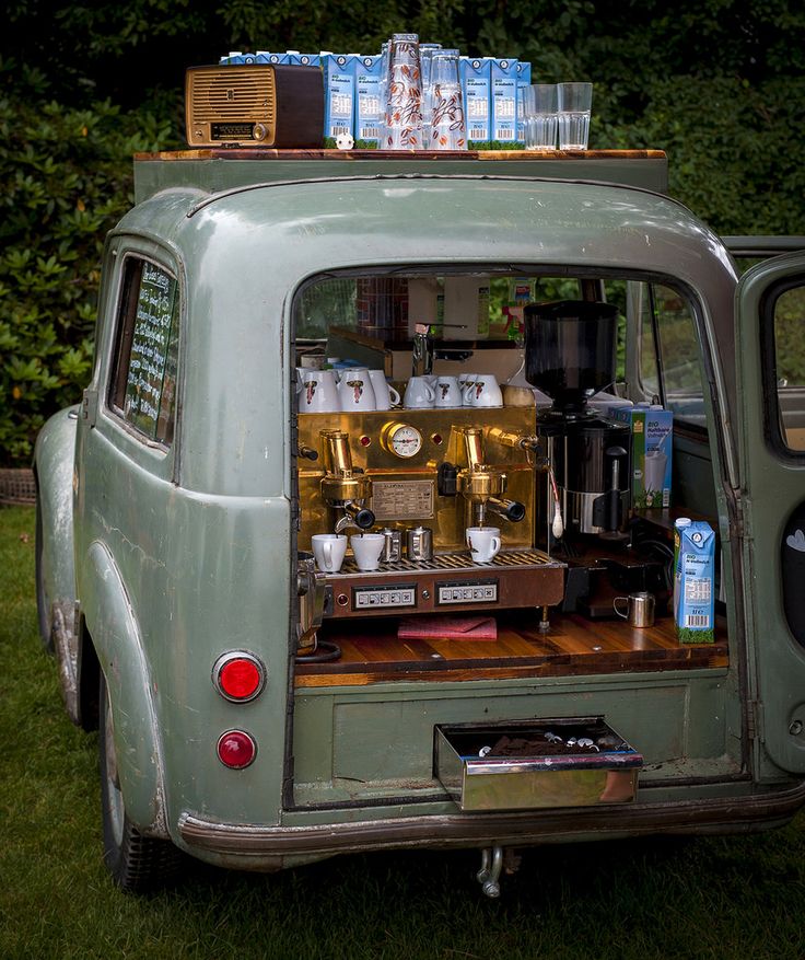 an old green van is parked in the grass with its back door open and coffee maker on top