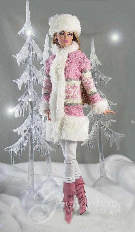 a barbie doll is standing in front of a snow - covered christmas tree with lights