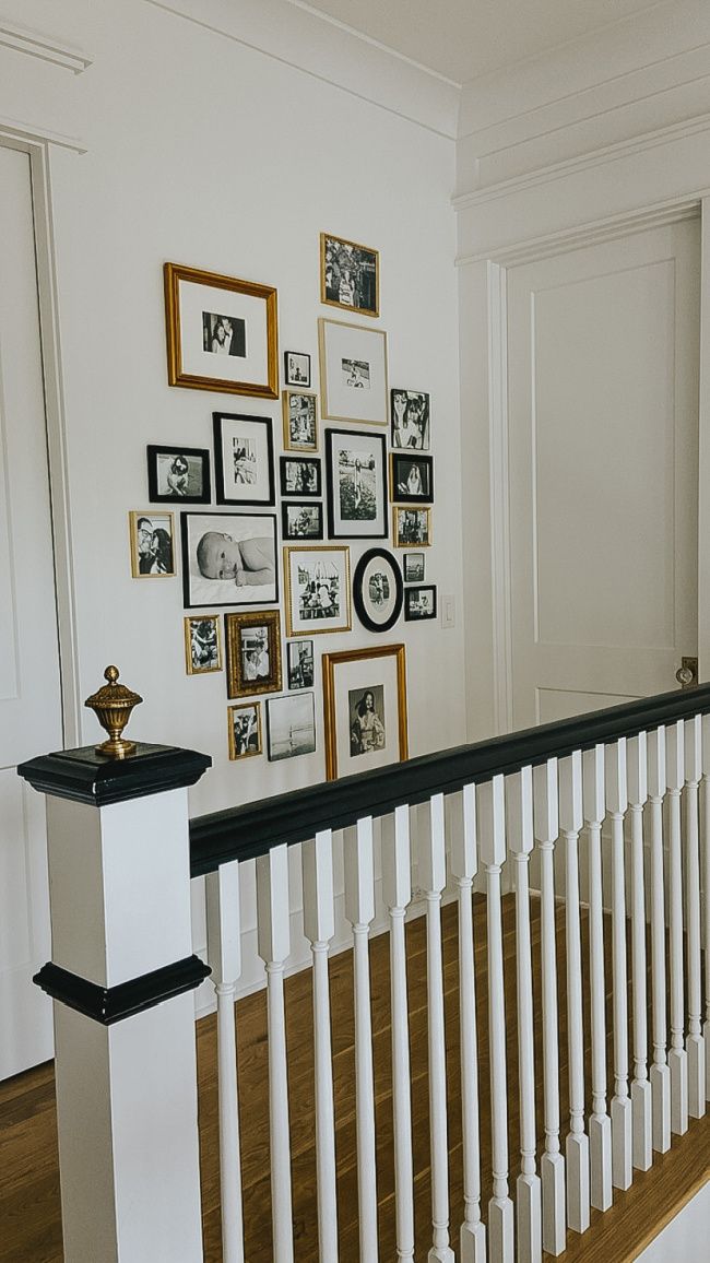 a staircase with white railing and pictures on the wall