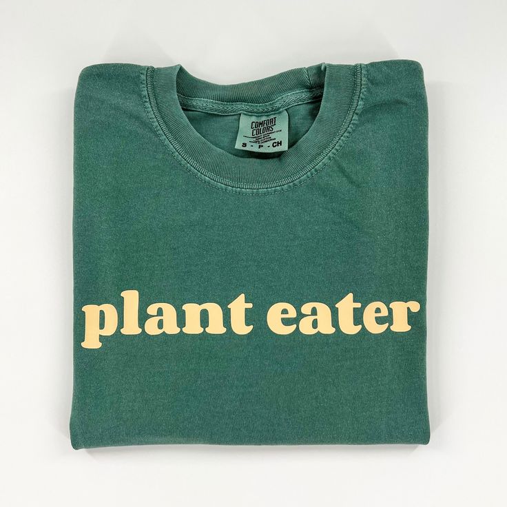 "This comfy vegan activism t-shirt features our \"Plant Eater\" graphic on the front and is blank on the back. Material: 100% ringspun cotton that is preshrunk, soft-washed, and made from garment-dyed fabric. Fit: Unisex. Make sure to check the size chart (swipe through photos). Care: Wash inside out and tumble dry low or hang dry. Do not iron or dry clean." Eco-friendly Green Cotton T-shirt, Everyday Screen Print T-shirt In Ring-spun Cotton, Organic Cotton Graphic Tee With Logo Print, Eco-friendly Organic Cotton Tops With Screen Print, Earth Day Text Print Crew Neck Top, Organic Cotton Crew Neck T-shirt, Organic Short Sleeve T-shirt With Screen Print, Earth Day Graphic Tee With Crew Neck, Sustainable Cotton Tops With Screen Print