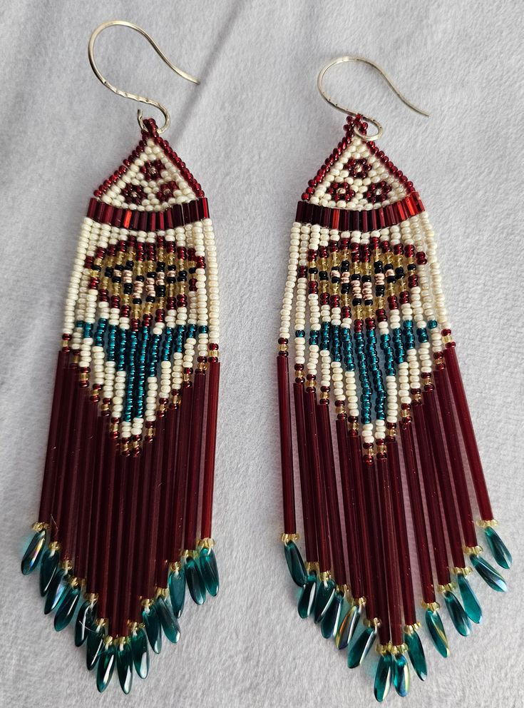 two pairs of beaded earrings with fringes and beads hanging from them on a white surface