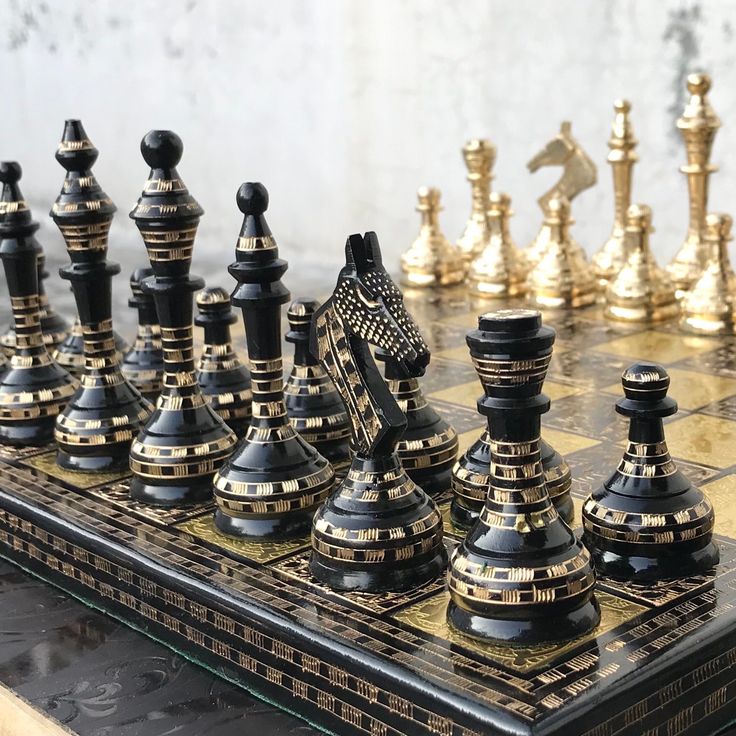 a chess board with black and gold pieces on it