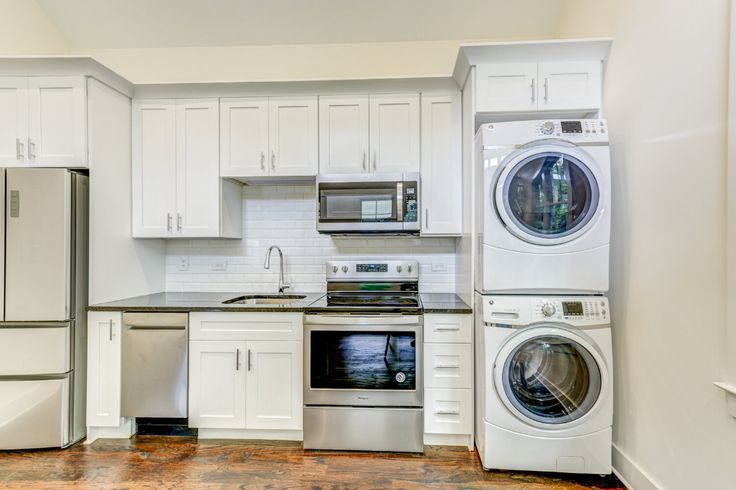 a kitchen with white cabinets and stainless steel appliances, including a washer and dryer