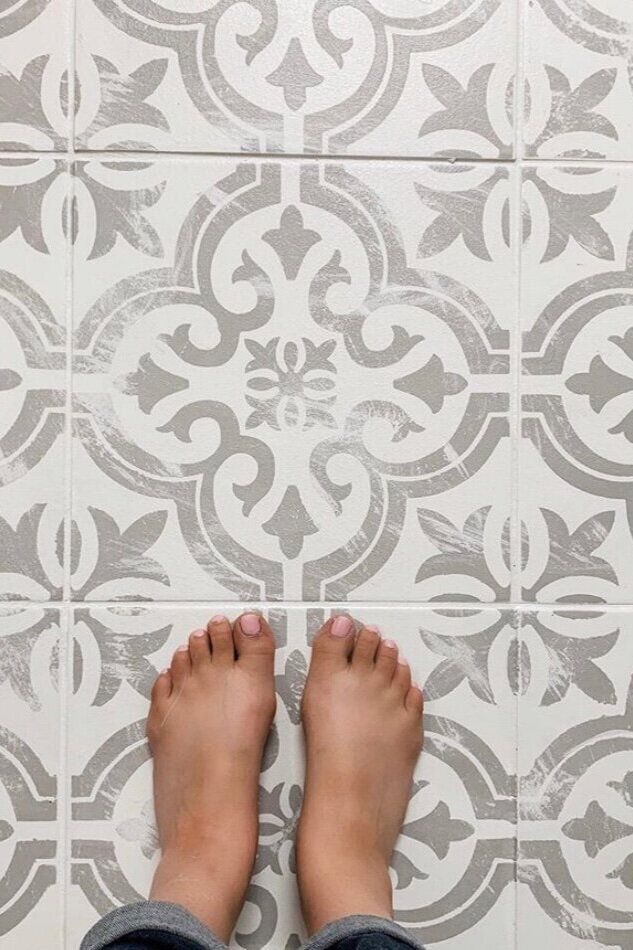 a person standing on a tile floor with their feet up in front of the tiles