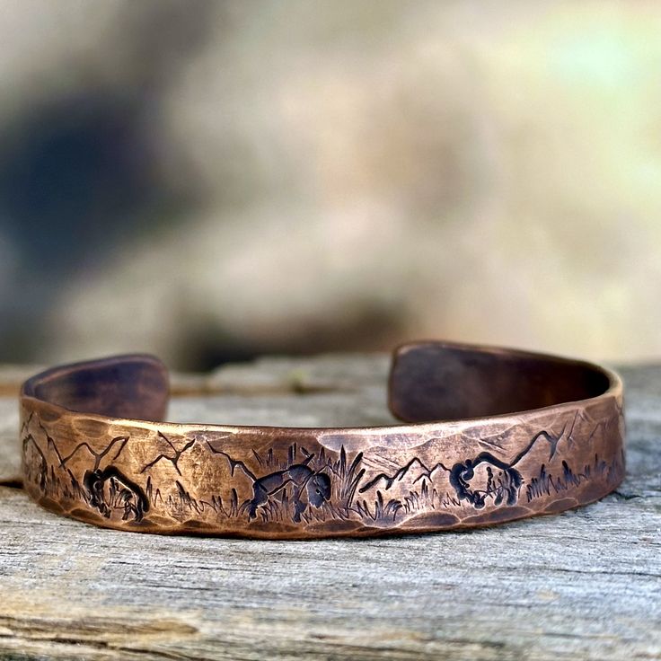 a close up of a metal bracelet on top of a piece of wooden planks