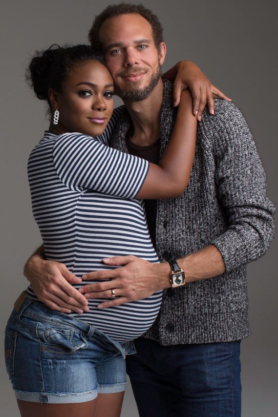 a man and woman hugging each other in front of a gray background with their arms around one another