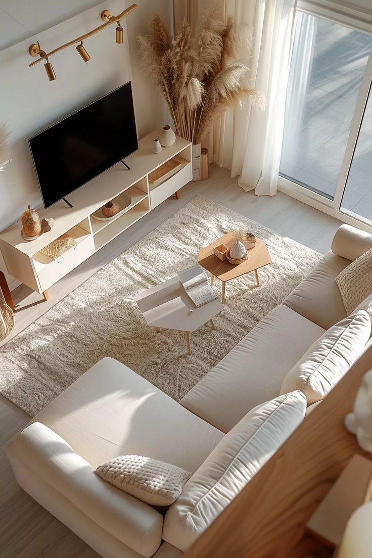 an overhead view of a living room with white couches and large television on the wall