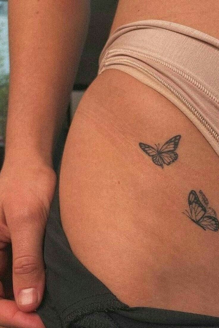 a close up of a person's stomach with two butterflies on the side of her belly