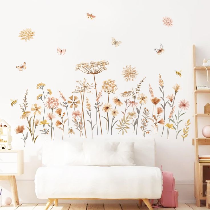 a white couch sitting in front of a wall with flowers and butterflies painted on it