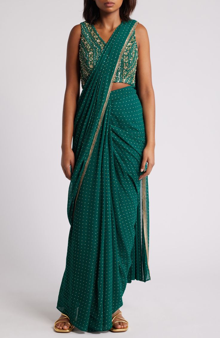 This saree has a hand-embroidered cropped top with intricate beadwork and lustrous sequins and is paired with a skirt featuring attached wraparound draping. This outfit is prestitched, so you can put it together in 30 seconds or less. V-neck Top has hook-and-eye closure; skirt has hidden side-zip closure Top and skirt feature hook-and-eye attachments for easy drape adjustments Lined 100% viscose Spot clean Made in India Asian & Pacific Islander Owned/Founded Embellished Georgette Pre-draped Saree, Traditional Embellished Pre-draped Saree For Festive Season, Festive Bollywood Embellished Pre-draped Saree, Bollywood Embellished Draped Lehenga, Bollywood Style Draped Embellished Lehenga, Embellished Draped Bollywood Lehenga, Traditional Pre-draped Art Silk Saree With Sequins, Bollywood Style Embellished Pre-draped Saree, Festive Embellished Draped Lehenga