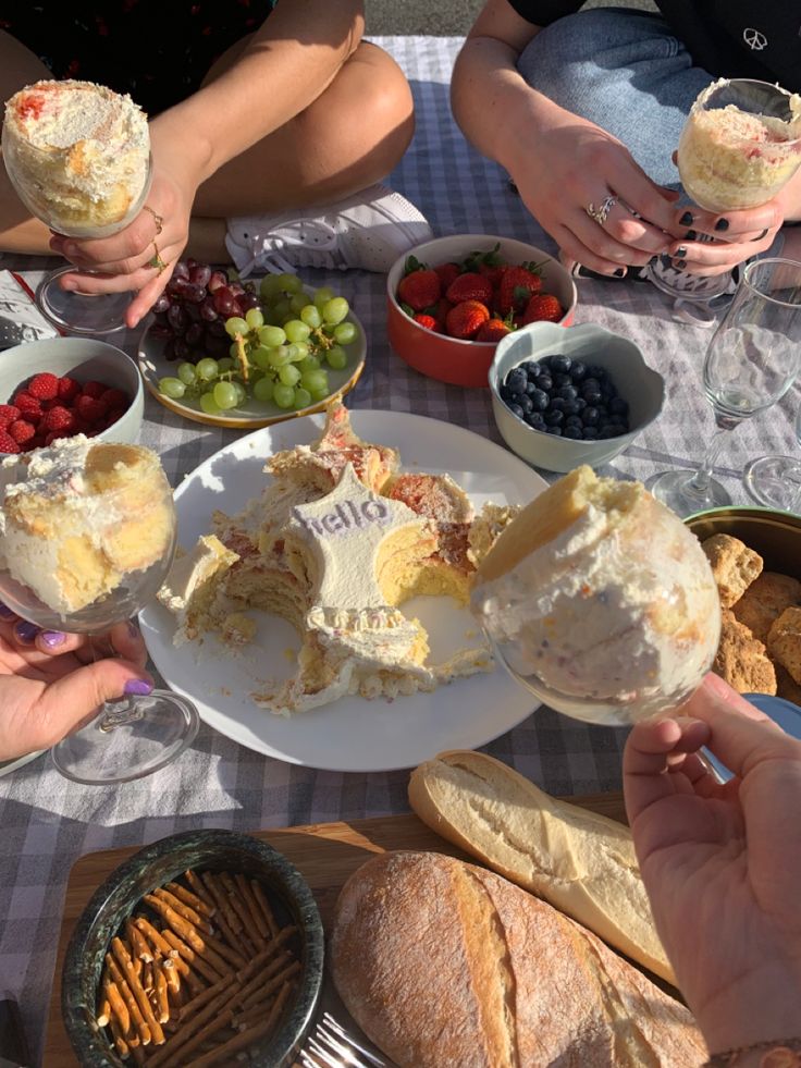 people sitting at a table with food and wine glasses in front of them, one person holding up a piece of cake