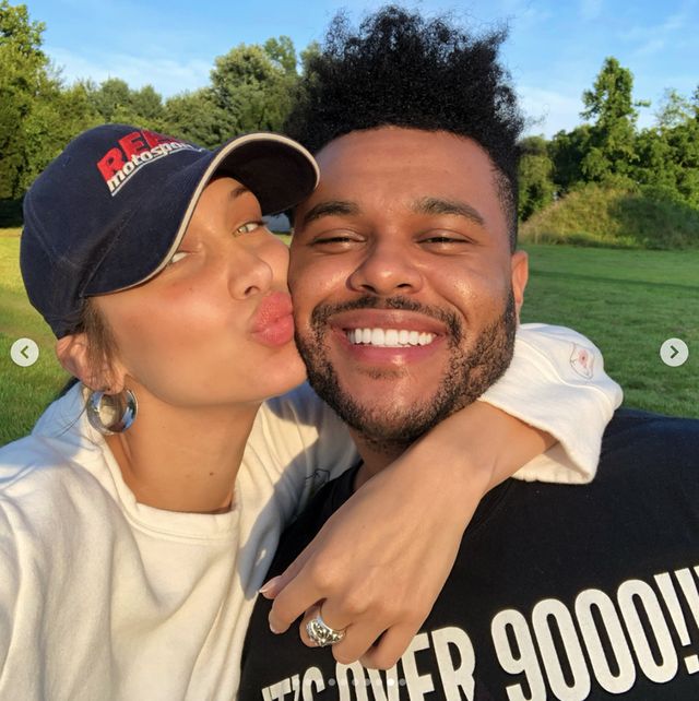 a man and woman are posing for a photo in the park, one is kissing the other's cheek