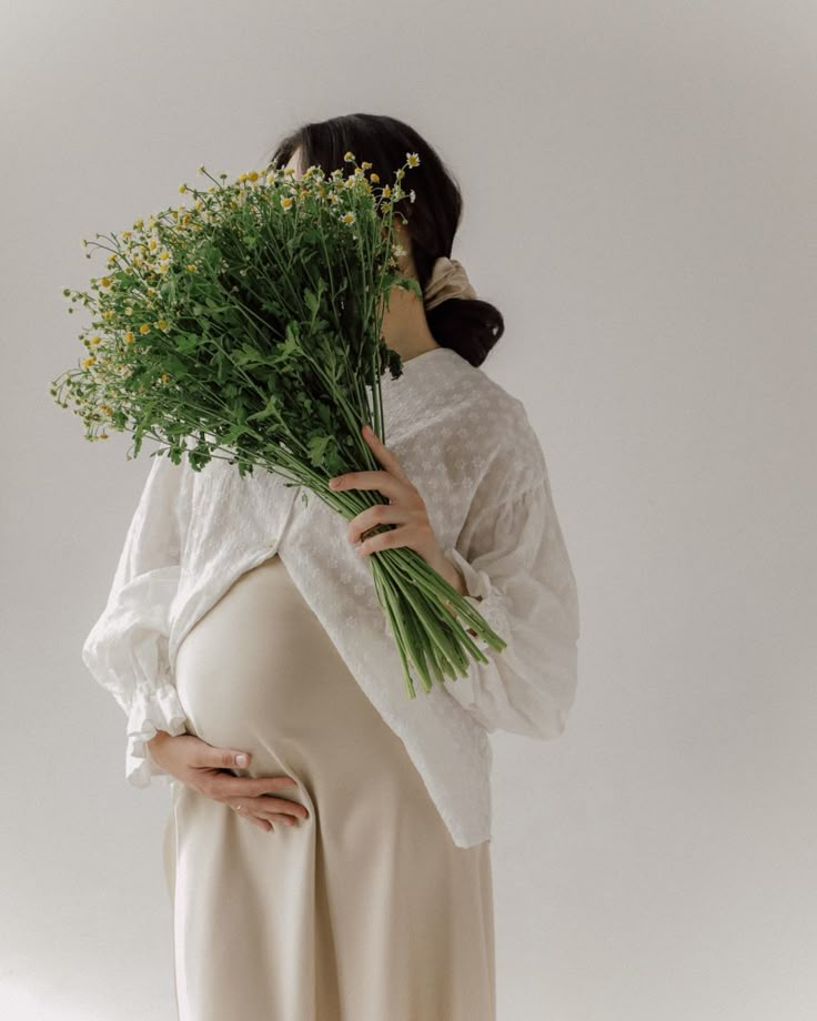 a pregnant woman holding flowers in her belly