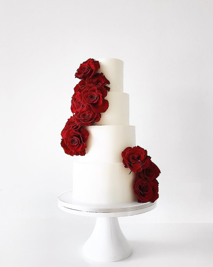 a three tiered white cake with red flowers on top