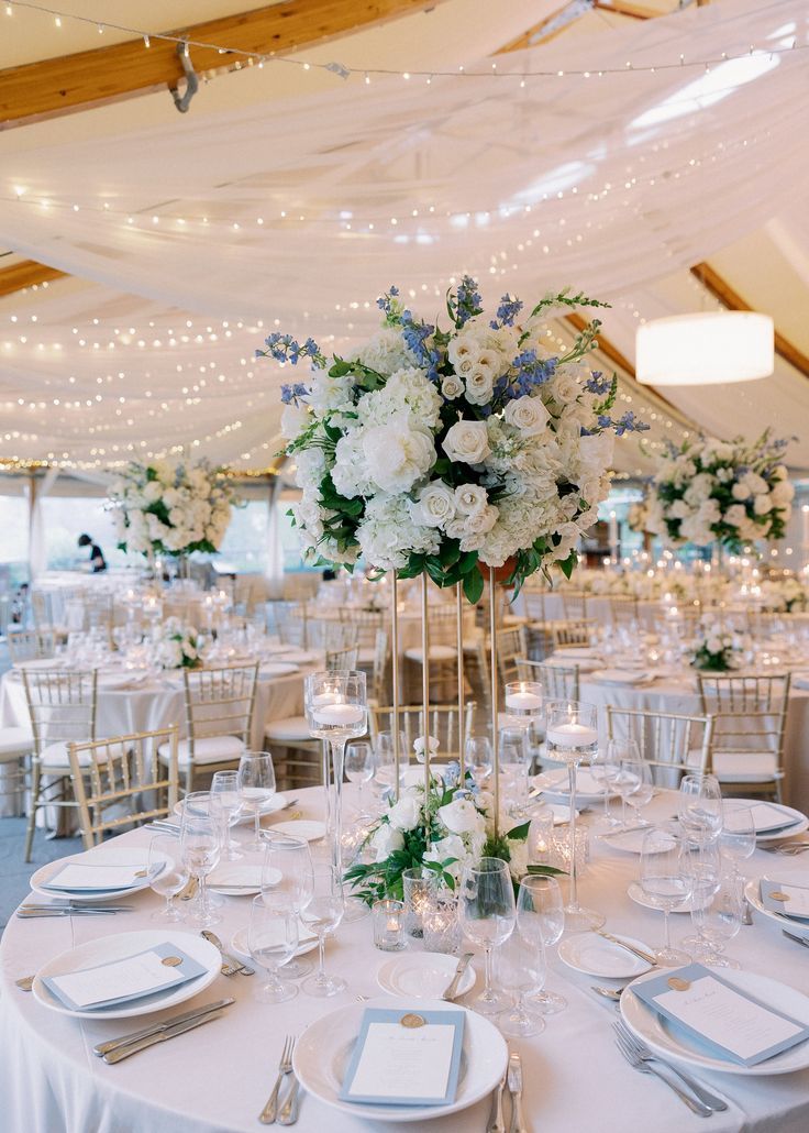 a table set up with white and blue flowers