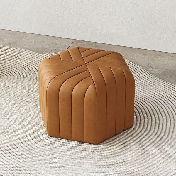 a brown ottoman sitting on top of a rug next to a white wall and floor