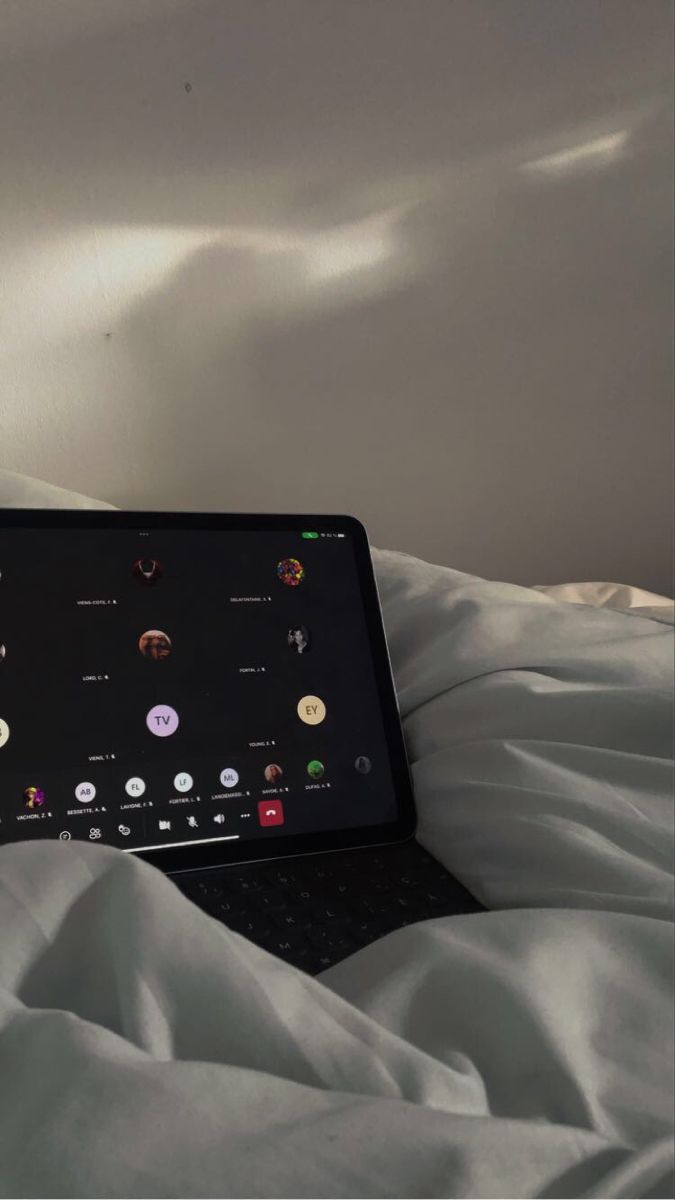 an open laptop computer sitting on top of a white bed covered in sheets and blankets