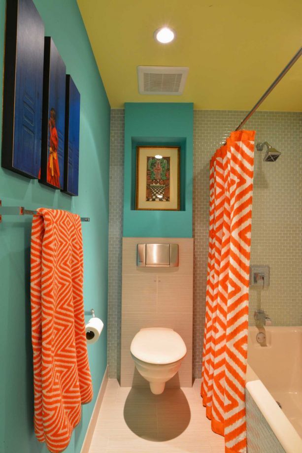 a bathroom with blue walls and orange towels on the shower curtain, toilet and bathtub