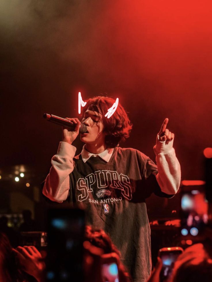 a young man holding a microphone in front of his face while standing on stage at a concert