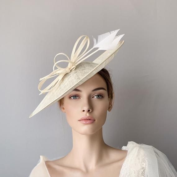 Cream sinamay derby fascinator, Ivory fascinator hat, bow feathers derby hat, Beige wedding hat, Royal ascot hat, women racing hat, saucer This cream sinamay fascinate hat is embellished with a big bow and two arrow feathers.It is a perfect hat for weddings, Royal Ascot horse races, cocktails, derby...It is mounted on a headband.If you want, you can choose the side of the head were you like to wear the fascinator, just convo me.Any color of the fascinator can be changed to order. Beige Headpiece For Kentucky Derby Event, Sinamay Hat Fascinator For Royal Ascot, Elegant Wedding Top Hat With Feathers, Cream Event Hat, Sinamay Hat Fascinator For Kentucky Derby, Elegant Feather Fascinator For Church, Summer Sinamay Fascinator For Races, Elegant Church Fascinator With Feathers, Elegant Feathered Mini Hats For Weddings