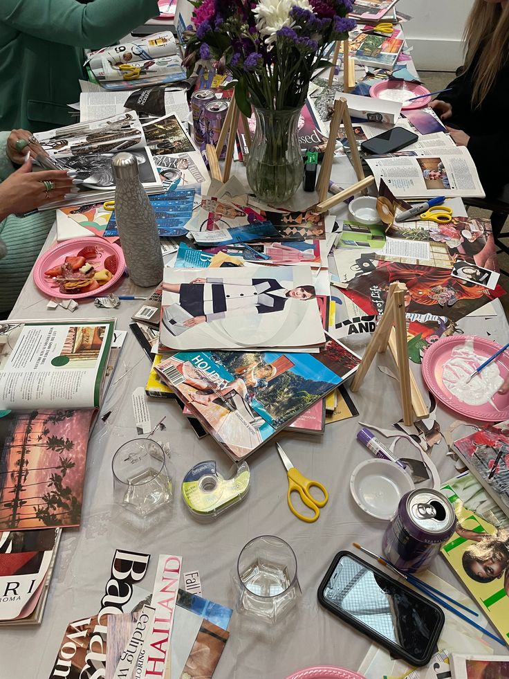 people sitting at a table covered with magazines and other items that are on the table