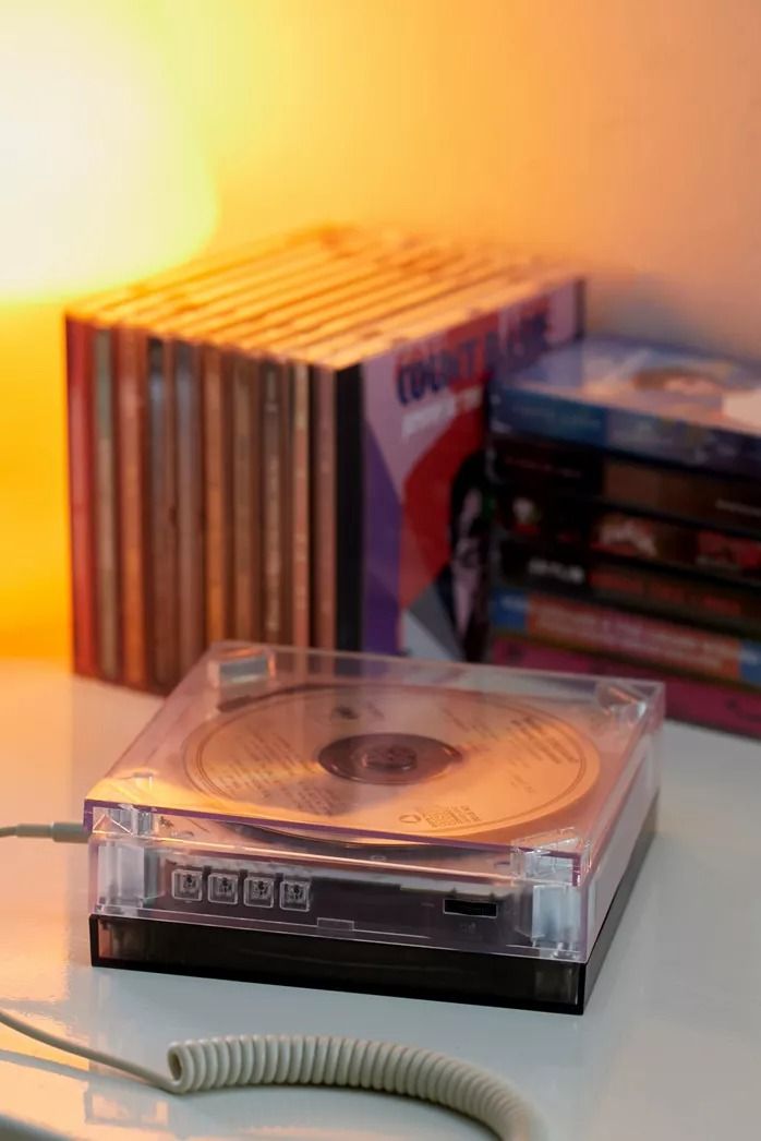 a cd player sitting on top of a table next to a lamp and dvd cases