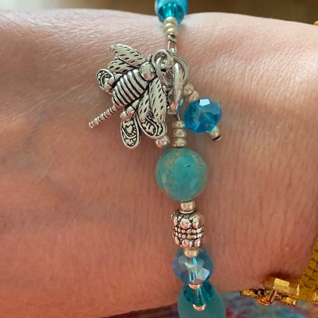 a close up of a person wearing a bracelet with beads and charms on their wrist