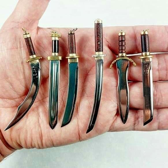 a person holding five different types of knives in their hand with gold trimmings