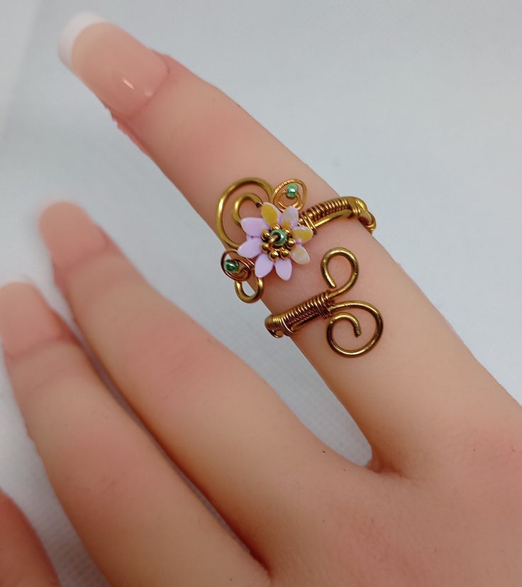 a person's hand with a ring on it that has flowers in the middle