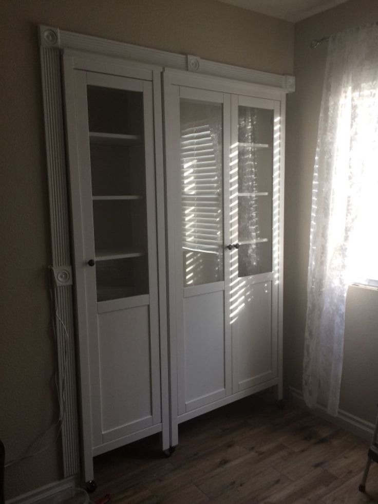 an empty room with white cupboards and curtains