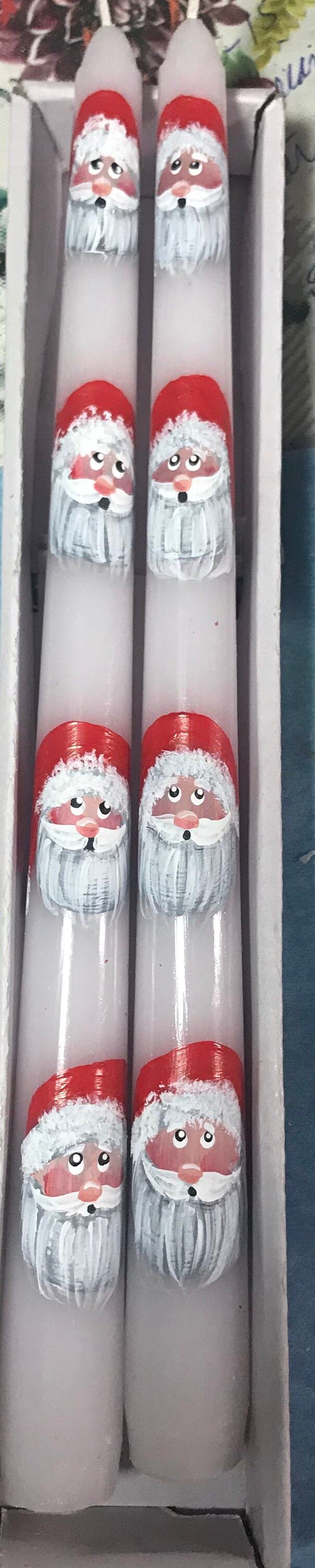 six santa claus candles in a box on a table