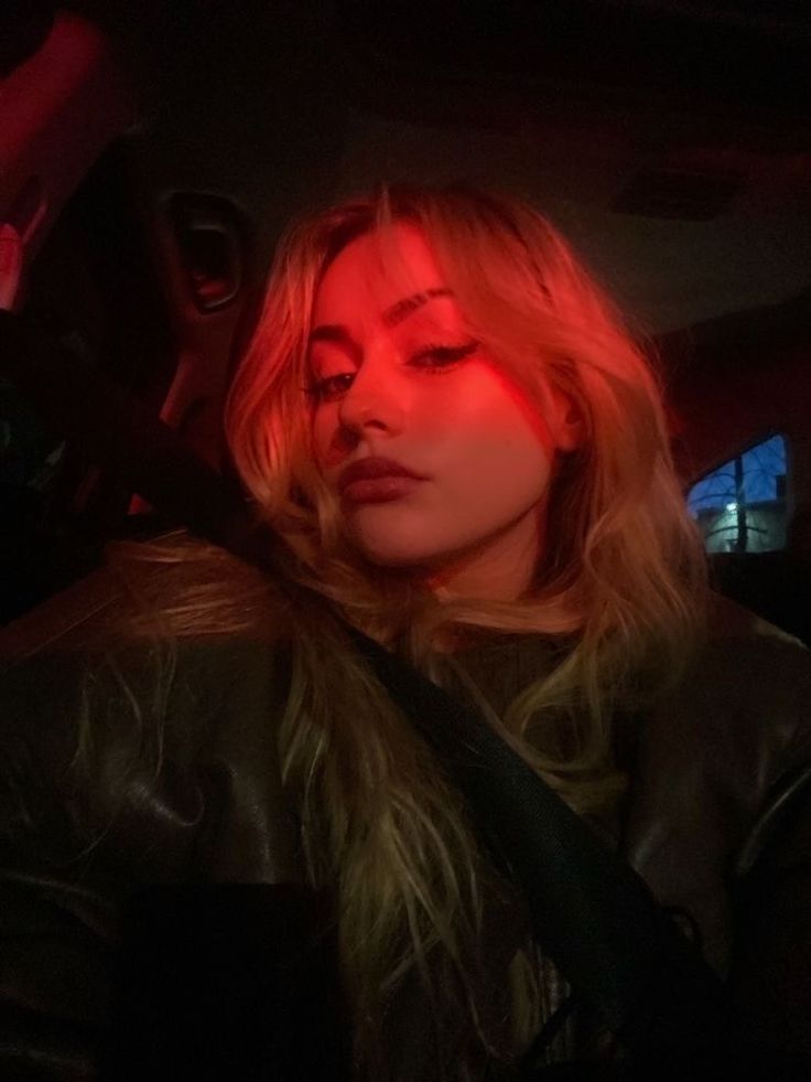 a woman sitting in the back seat of a car with red light on her face