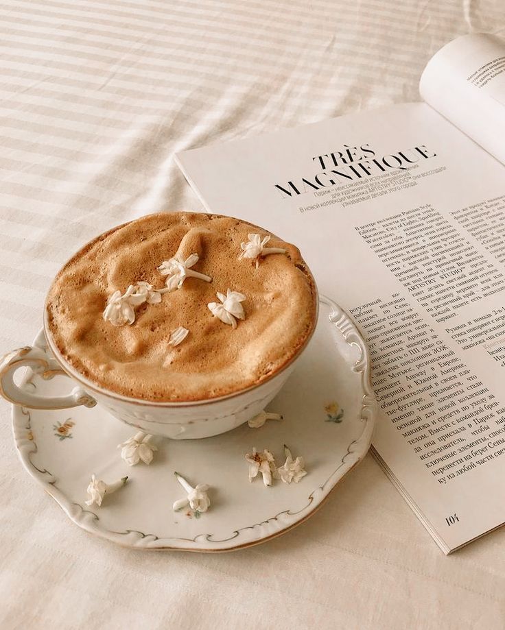 a cup of coffee sitting on top of a saucer next to an open book