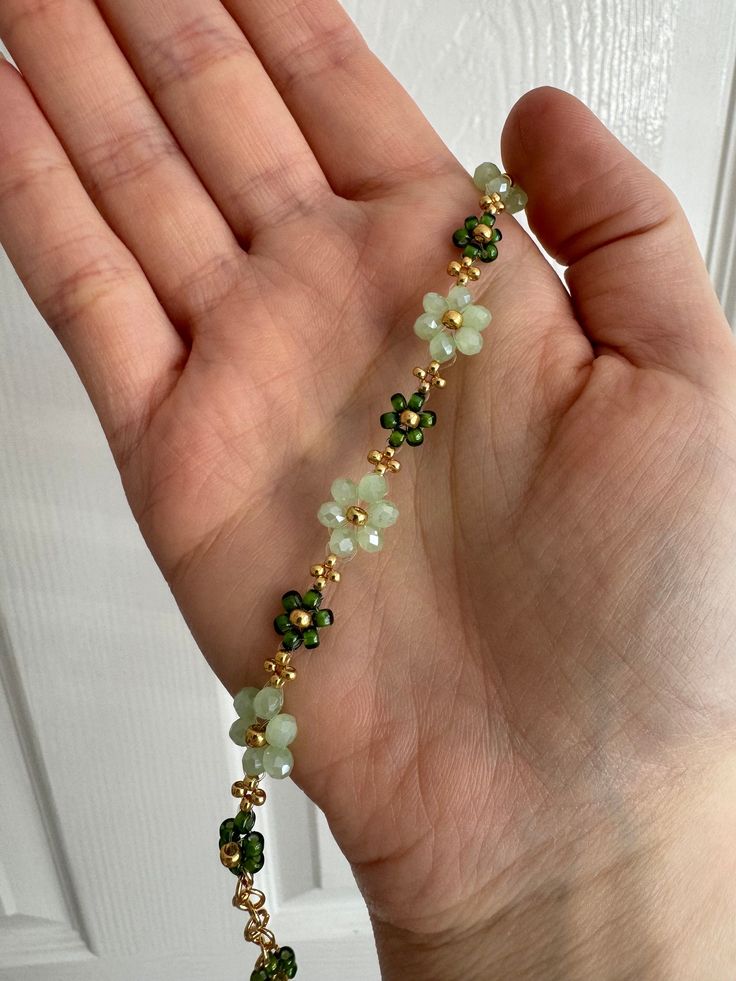 a hand holding a green beaded bracelet